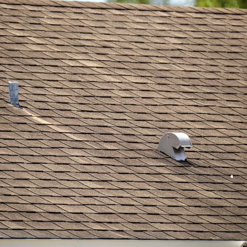 Closeup of house roof top covered with asphalt or bitumen shingles. Waterproofing of new building.